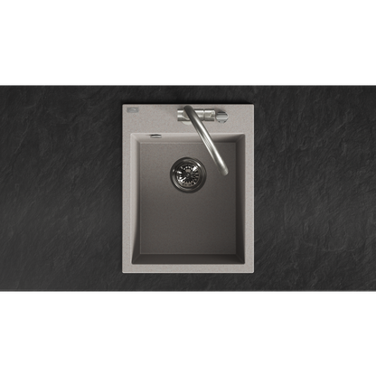 A top-down view of a modern single-basin kitchen sink with a brushed metallic interior, a matching curved faucet, and a light stone or concrete outer rim, set against a dark textured countertop.